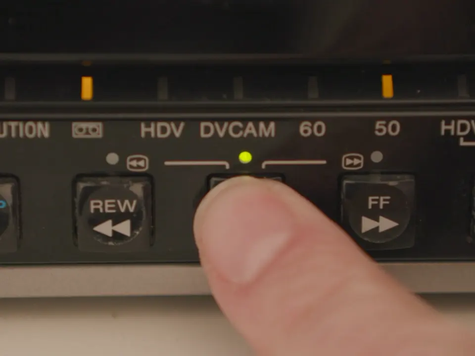 Prst pritišće tipku za reprodukciju na DVCAM uređaju